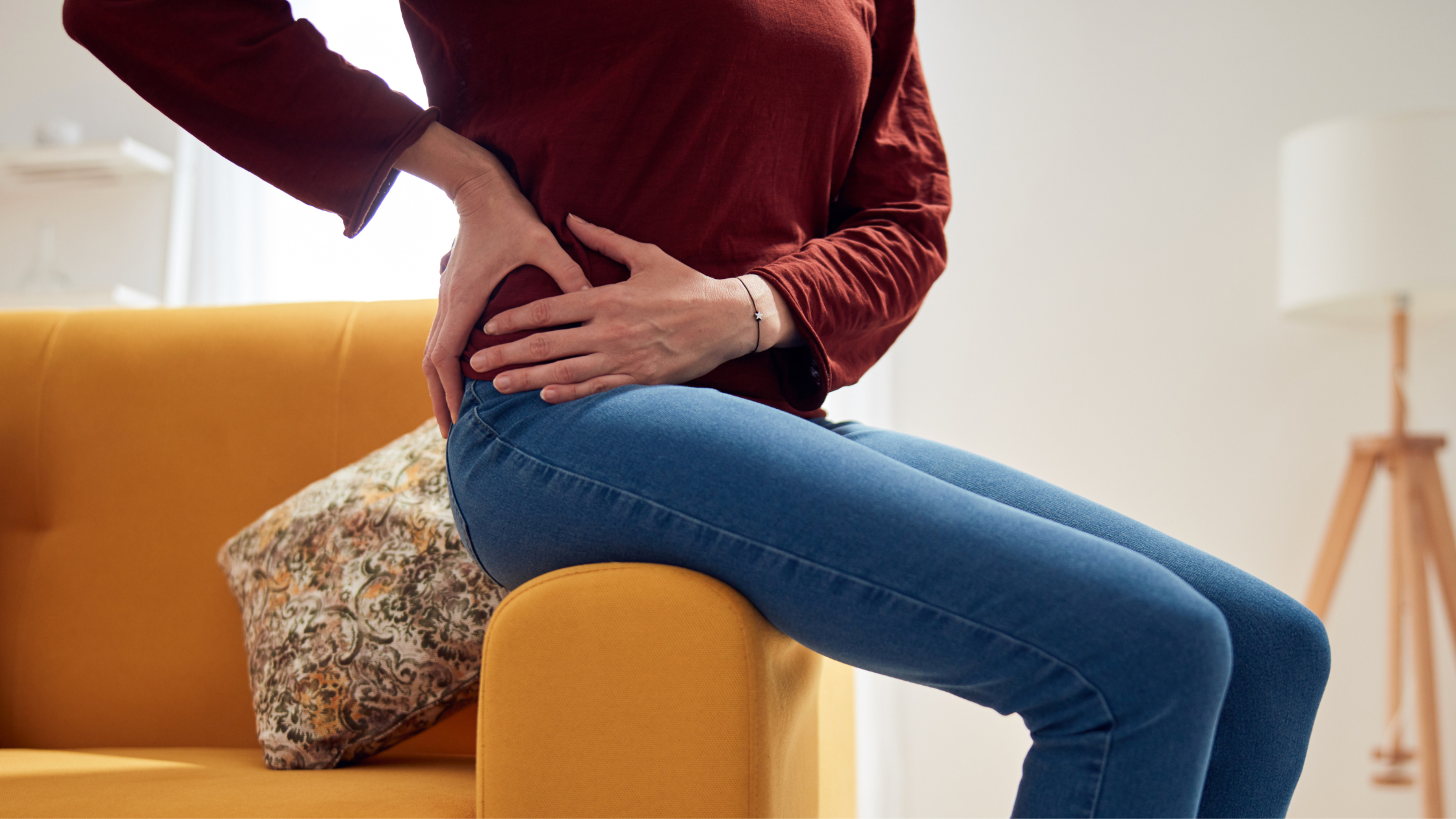 Woman in chronic pain, holding her lower back, near the side.