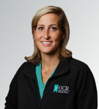 woman smiling, wearing a black jacket and a medical scrubs