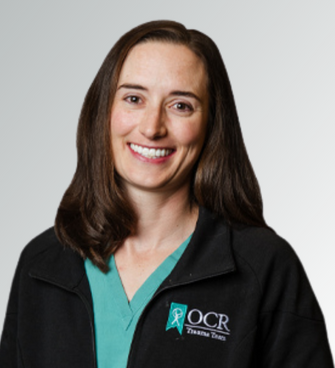 woman smiling, wearing a black jacket and a medical scrubs