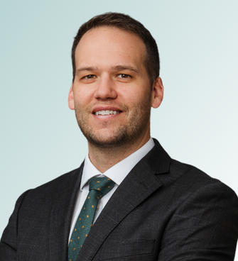 A man with short hair, a beard, and a friendly smile is wearing a dark gray suit, white dress shirt, and a dark green tie with a subtle pattern. Dr. Robert FitzGibbons, MD, stands against a light gradient background with his arms crossed.