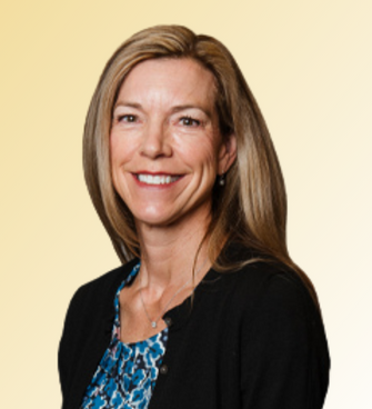 woman smiling, wearing a floral shirt and black cardigan