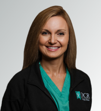 woman smiling, wearing a black jacket and a medical scrubs