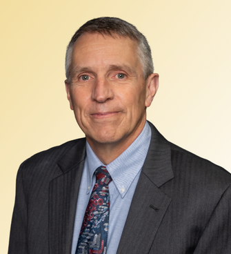 man smiling, wearing a suit and tie