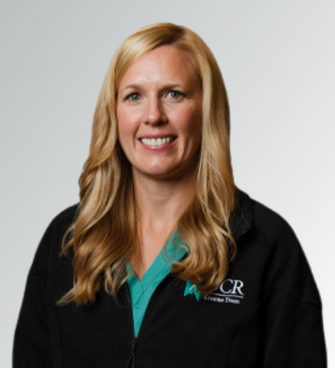 woman smiling, wearing a black jacket and a medical scrubs