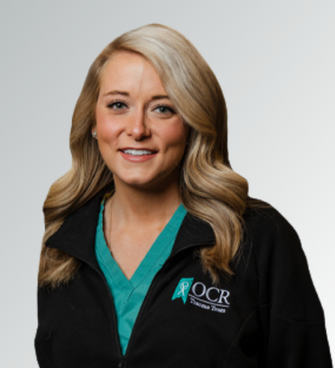 woman smiling, wearing a black jack and a medical shirt