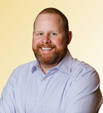 man smiling, wearing a checkered shirt