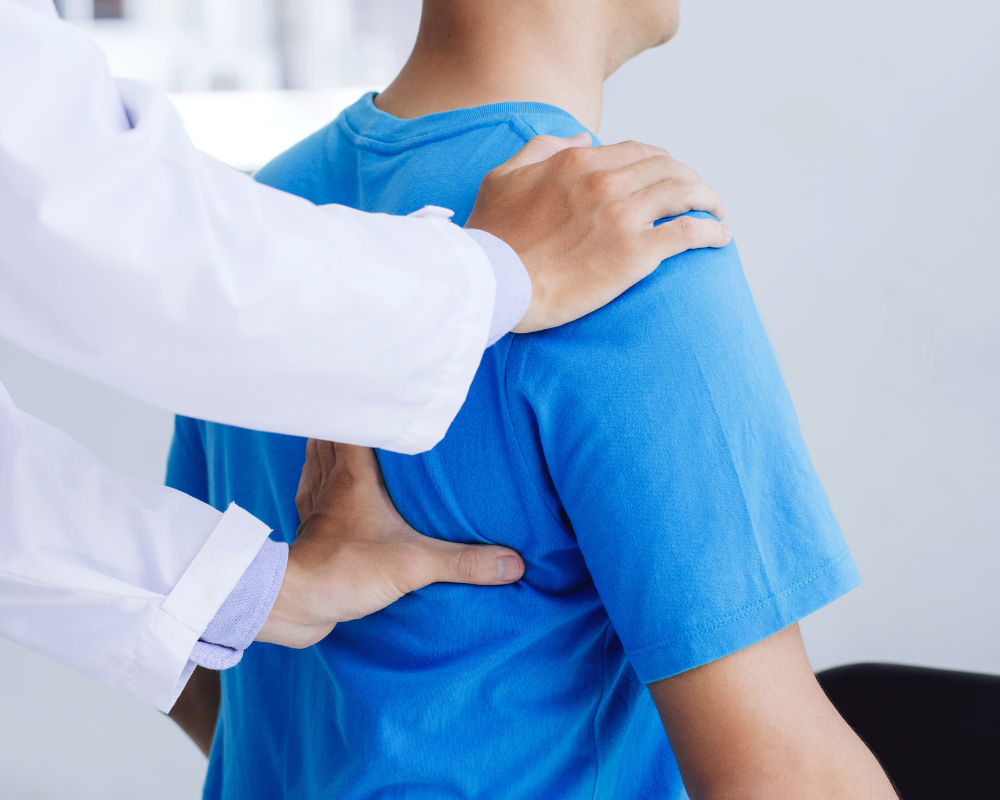 a man in a blue shirt getting his shoulder examined by a doctor