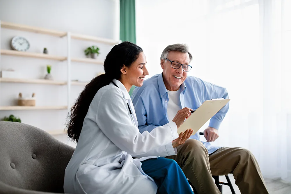 doctor talking with patient, both of them looking at forms