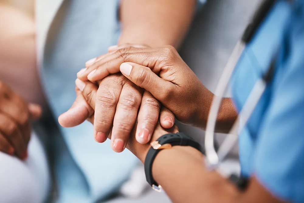 nurse holding hands with older patient