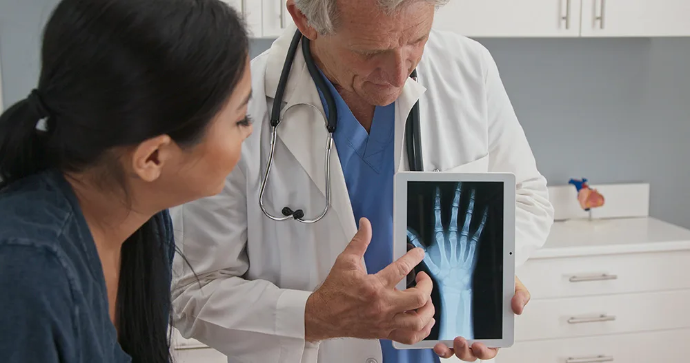 woman looking at x-ray of a hand with a doctor