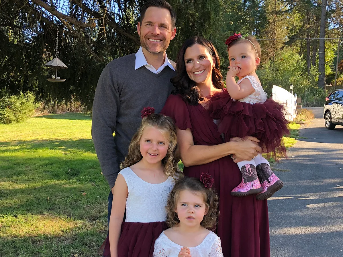 a family of five standing in green grass in front of a tree