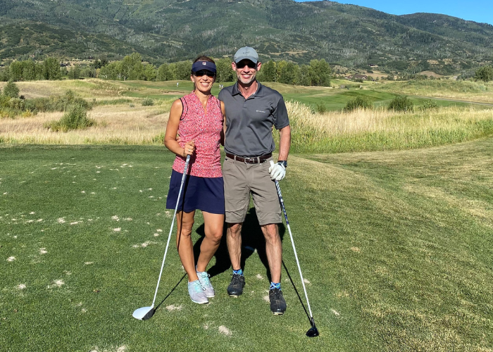 A couple holding golf clubs on a golf course