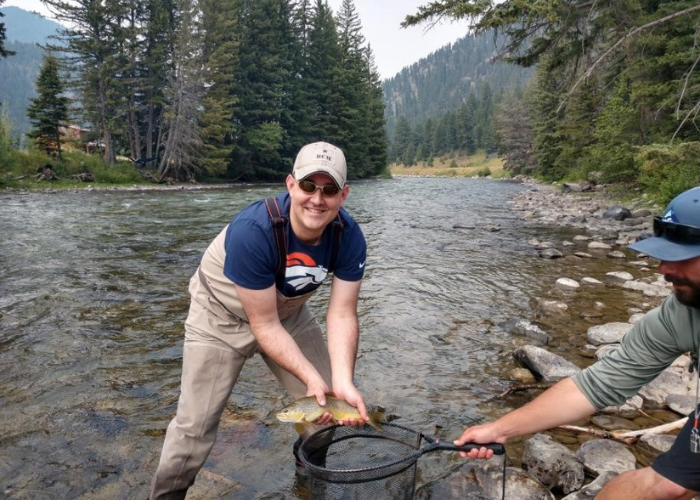 a man standing in a river holding a fish