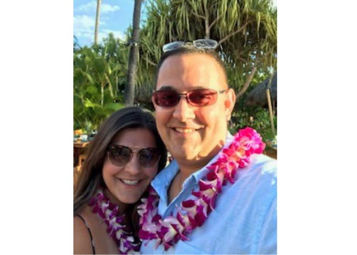 A man and a woman taking a selfie with flowers around their necks