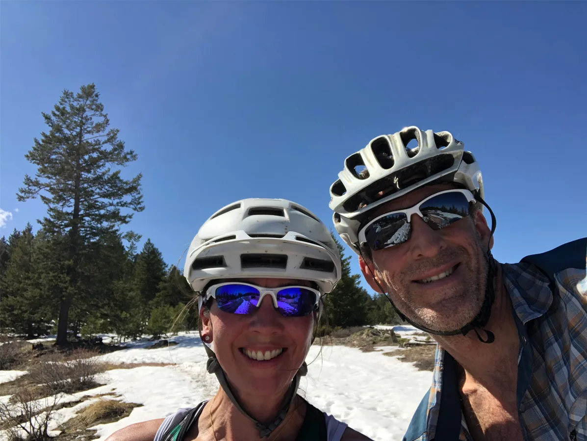 A man and a woman in bike helmets and sunglasses