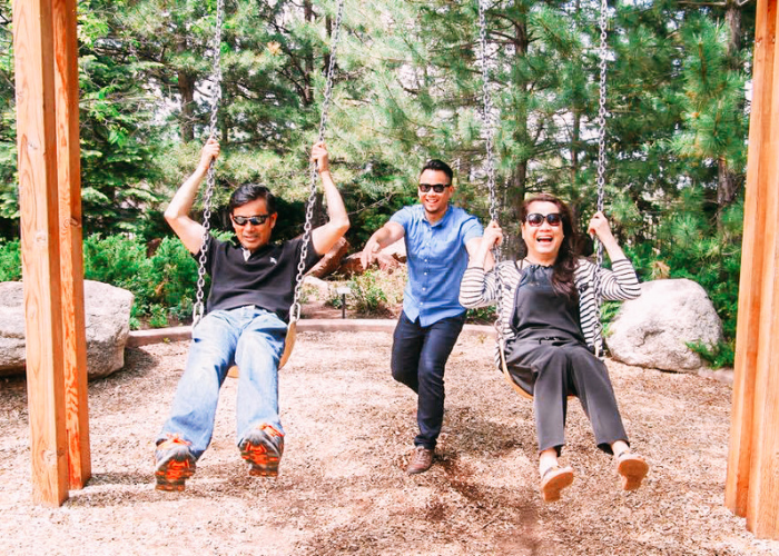 A man pushing two people on a swing set