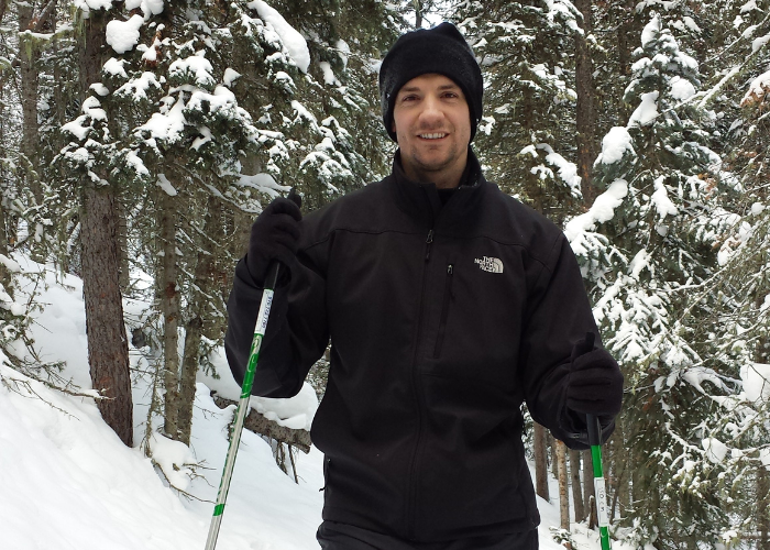 a man standing in a black snow suit in the woods