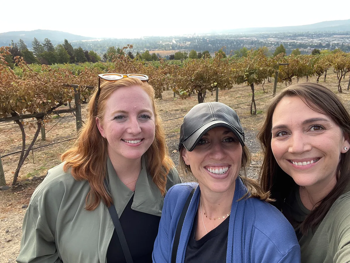 three women standing in a wine vineyard