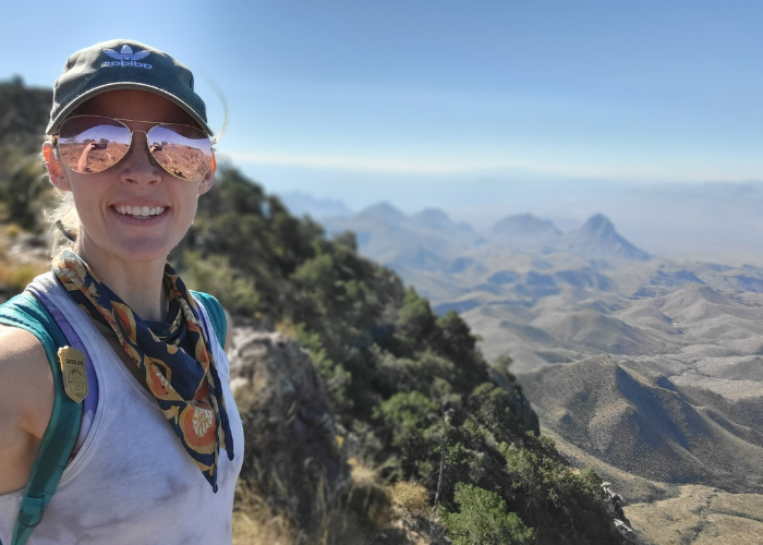 woman on a hike with mountains behind her