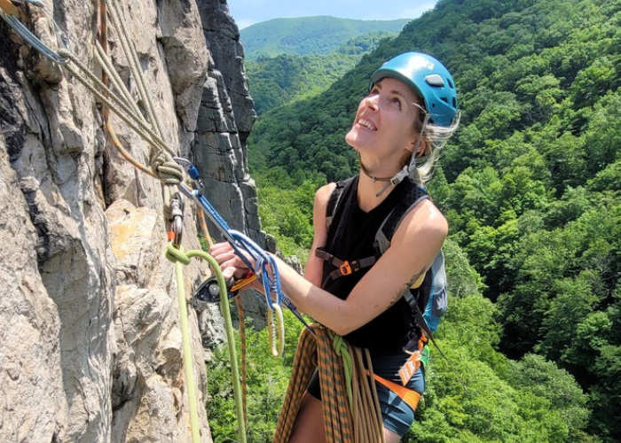 woman rock climbing with blue helmet