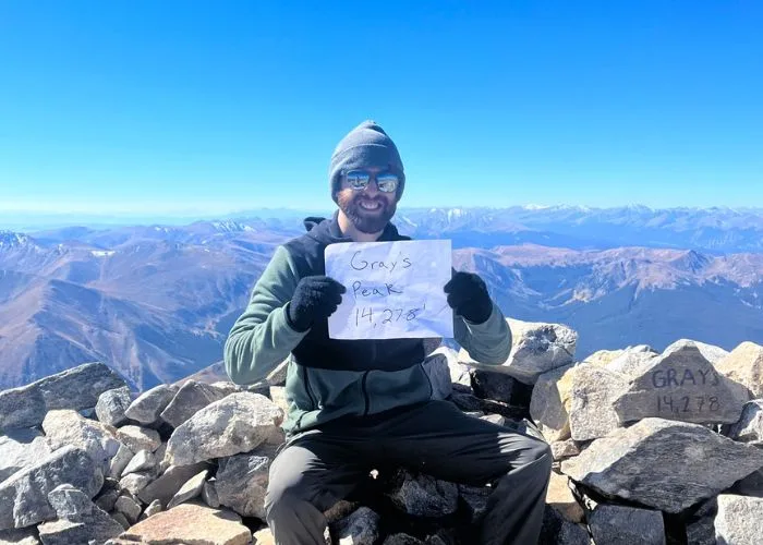 person on top of mountain holding a sign