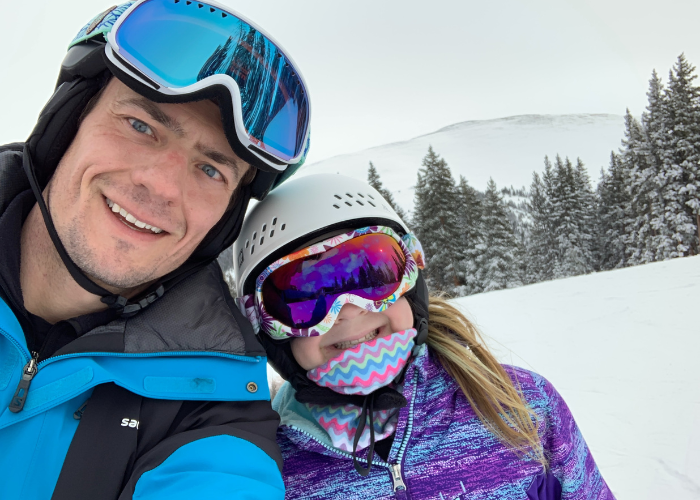 A man and a kid in snow gear on a mountain