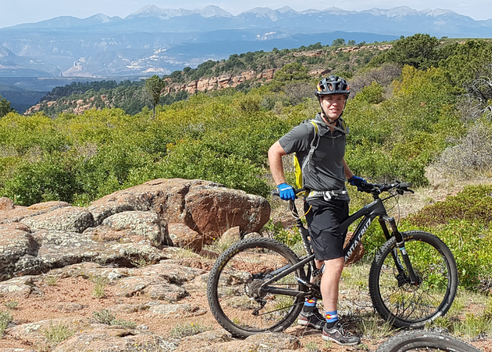 A man standing next to his bike on a mountain