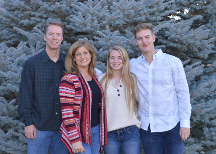 A family of four standing in front of a tree