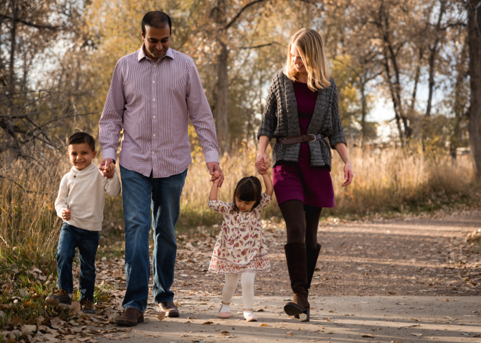 A man and woman with two children walking down a path in fall