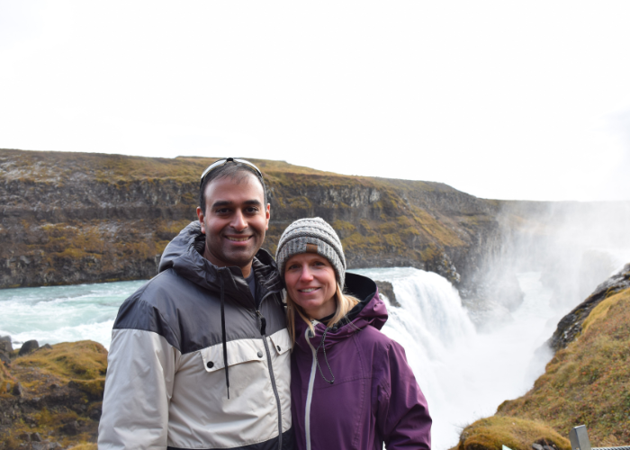 A man and a woman standing in front of a waterfall