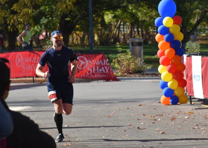 man running a race with colorful balloons behind him