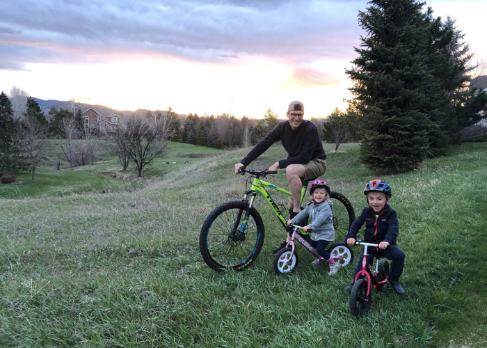 a man and two kids on bikes with the sunset