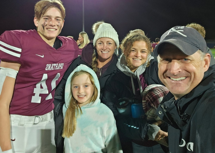 a family of 5 taking a selfie on a football field