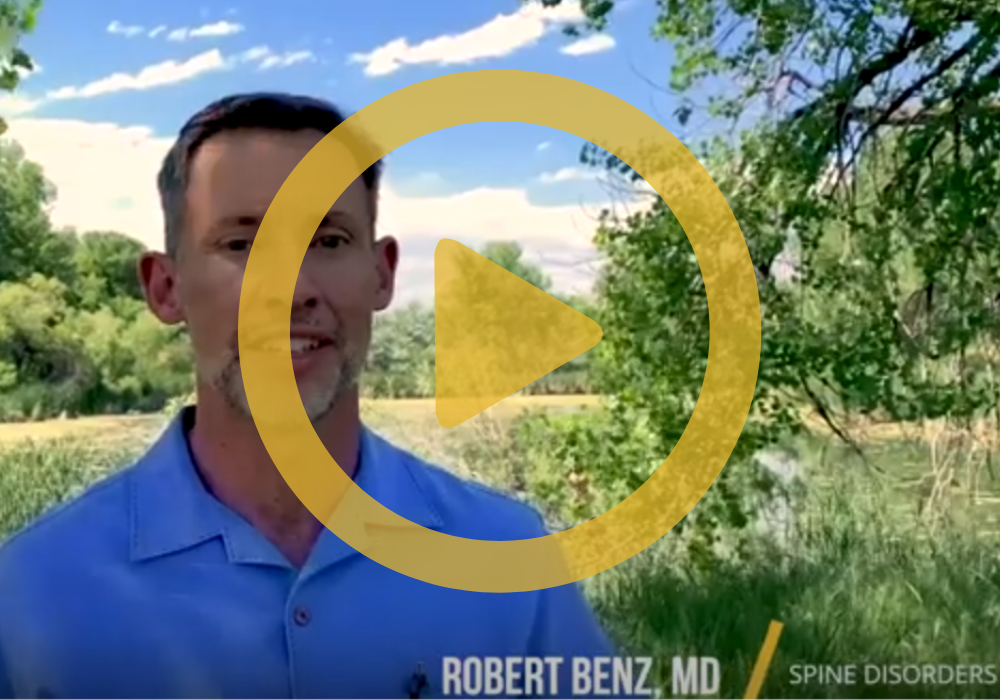 Dr. Benz standing outside under a tree with a yellow play icon