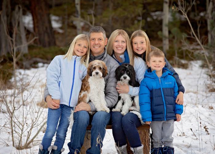 A family of 5 in the snowy mountains posing for a picture